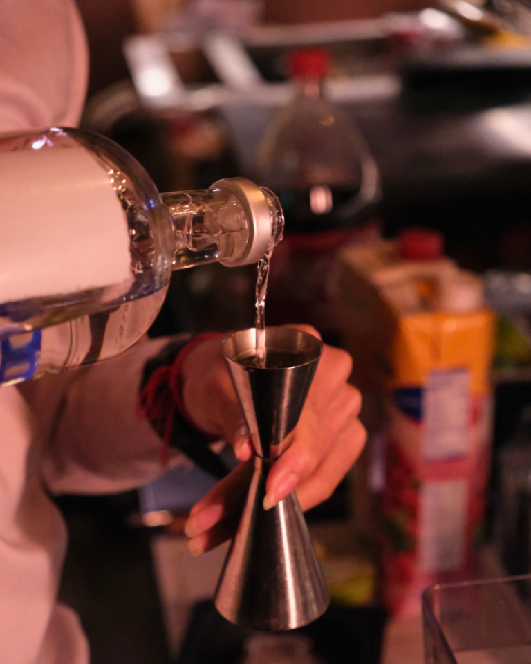 Bartender pouring alcohol into a cocktail shaker