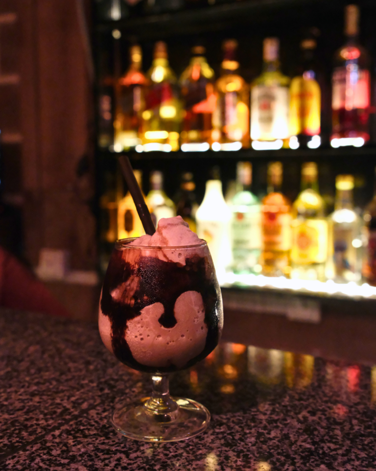 Chocolate dessert cocktail on bar counter with bottles in background